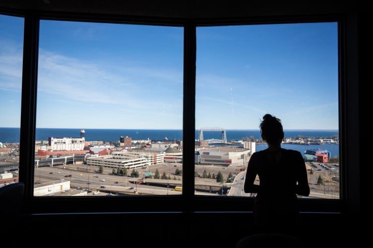 A silhouette of a woman with her hair in a bun, staring out over downtown Duluth, Minnesota, on a sunny day.