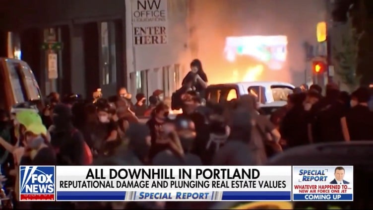 A crowd of people on a street in front of smoke and fire with a chyron that says, “All downhill in Portland: Reputational damage and plunging real estate values.”