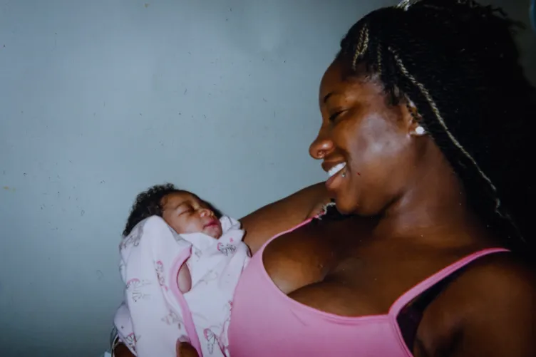 A woman smiles as she looks down at the baby she is holding.