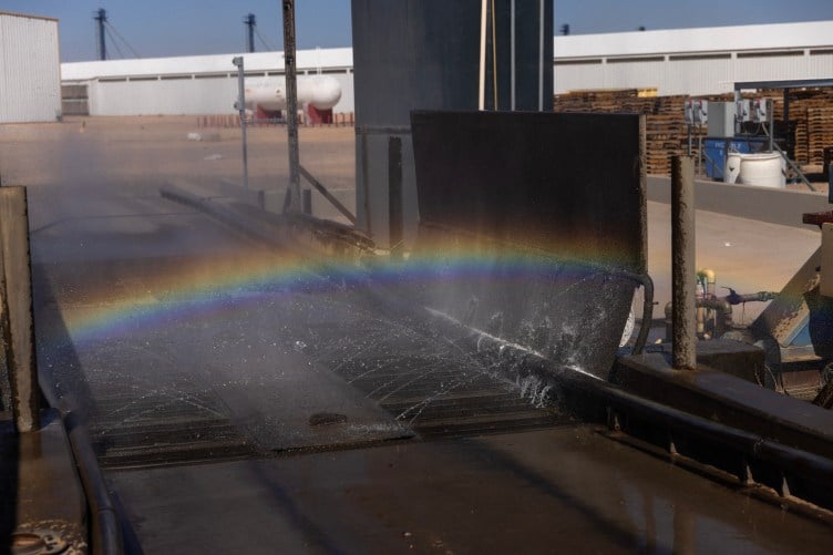 A rainbow appears in the misty water at a car wash.