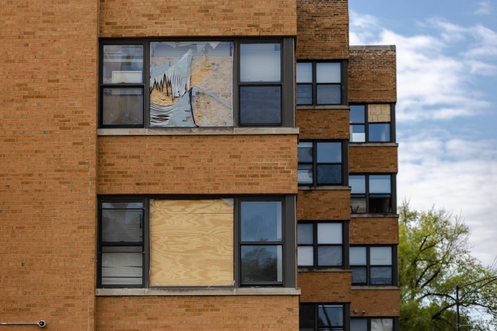 Fenêtres brisées et barricadées d'un immeuble en briques marron clair.