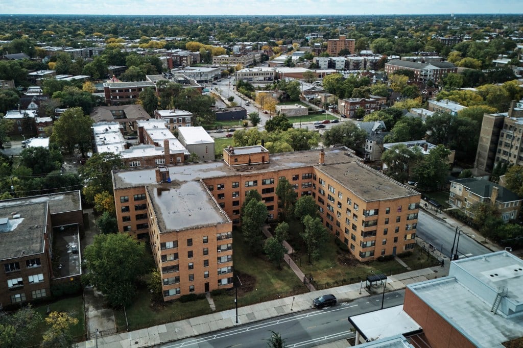Un grand bâtiment résidentiel en brique marron clair en forme de U dans un cadre urbain, vu d'en haut.