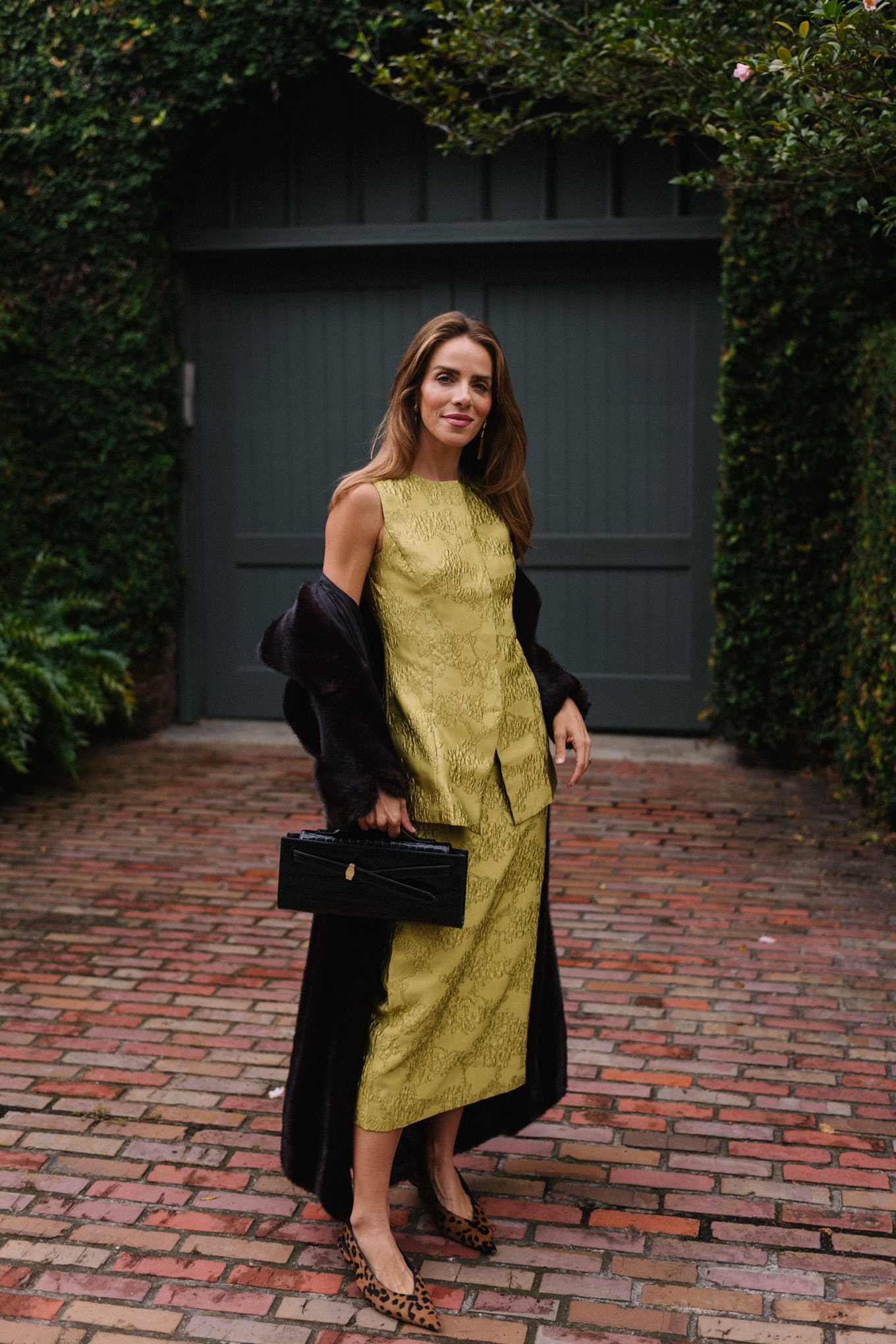 L'ensemble comprend un haut et une jupe chartreuse, un long manteau noir, un sac à main noir et des escarpins léopard