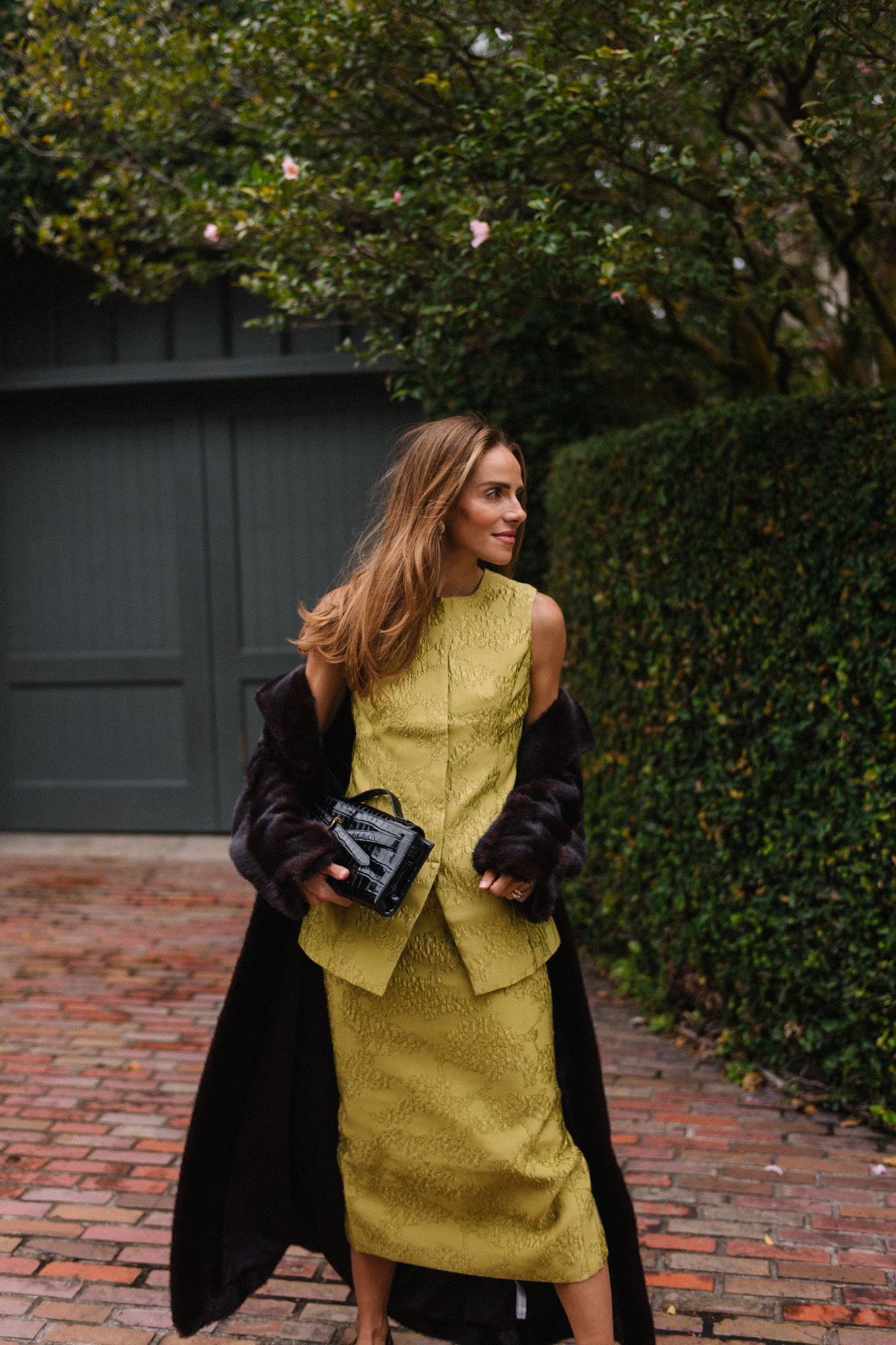 L'ensemble comprend un haut et une jupe chartreuse, un long manteau noir, un sac à main noir et des escarpins léopard