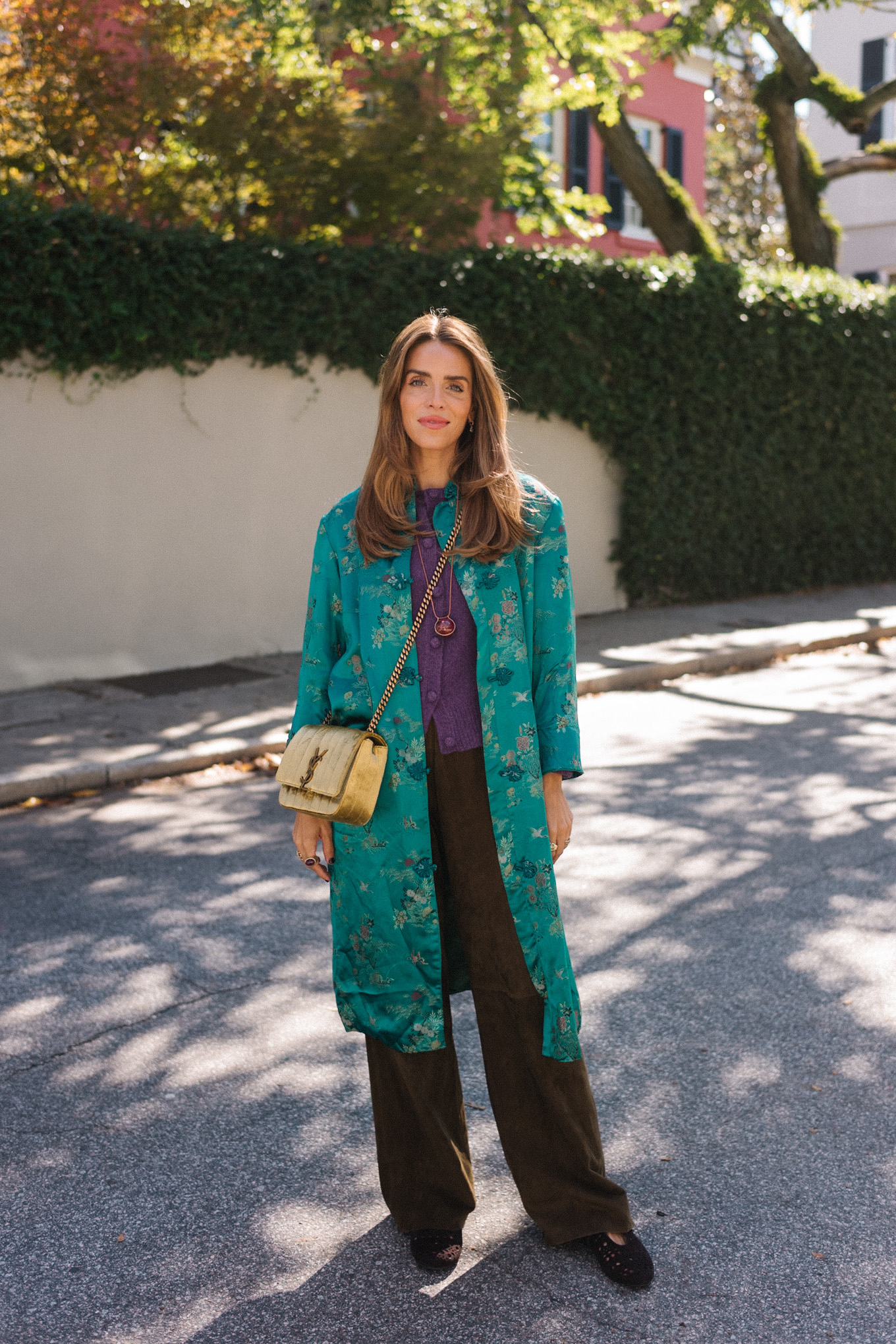 manteau en soie bleu sarcelle, pull en cachemire violet, pantalon en daim marron, sac en daim doré, ballerines marron