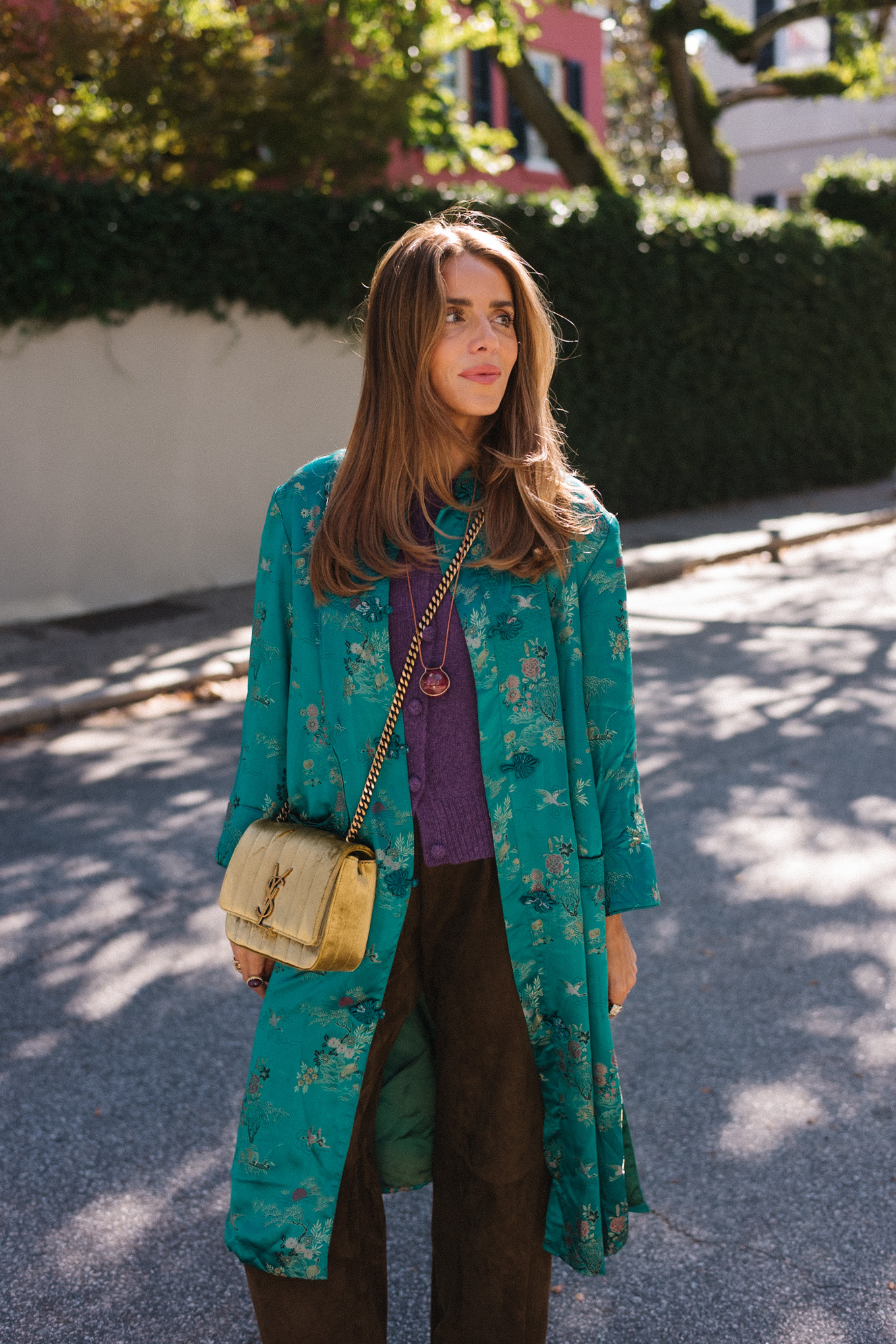 manteau en soie bleu sarcelle, pull en cachemire violet, pantalon en daim marron, sac en daim doré, ballerines marron