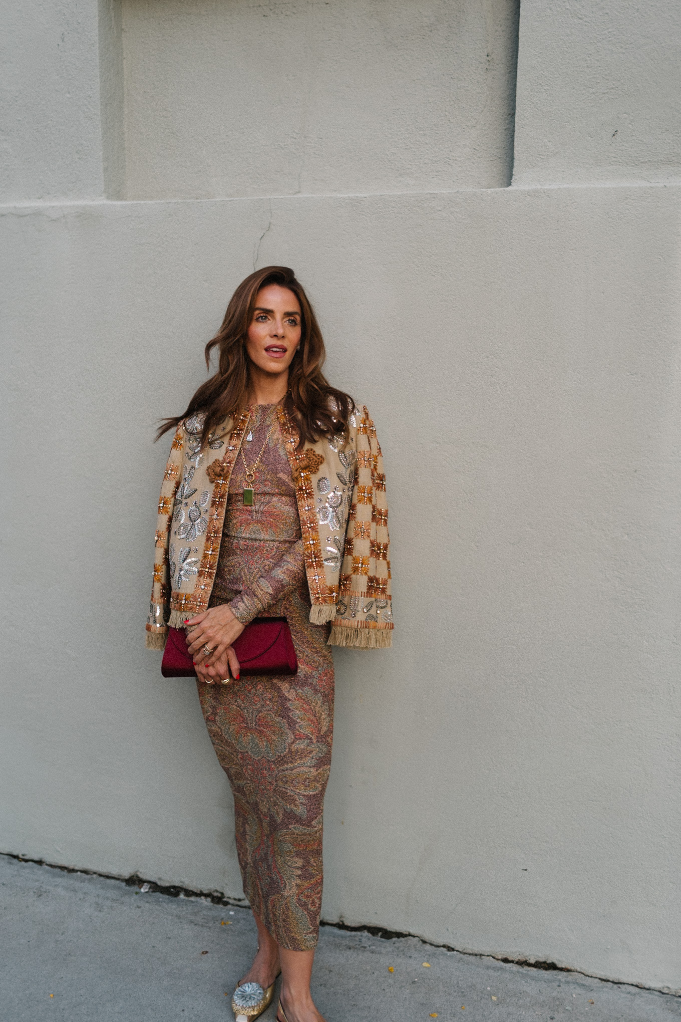 Veste ornée, jupe métallisée, chaussures plates à pompons, pochette en satin