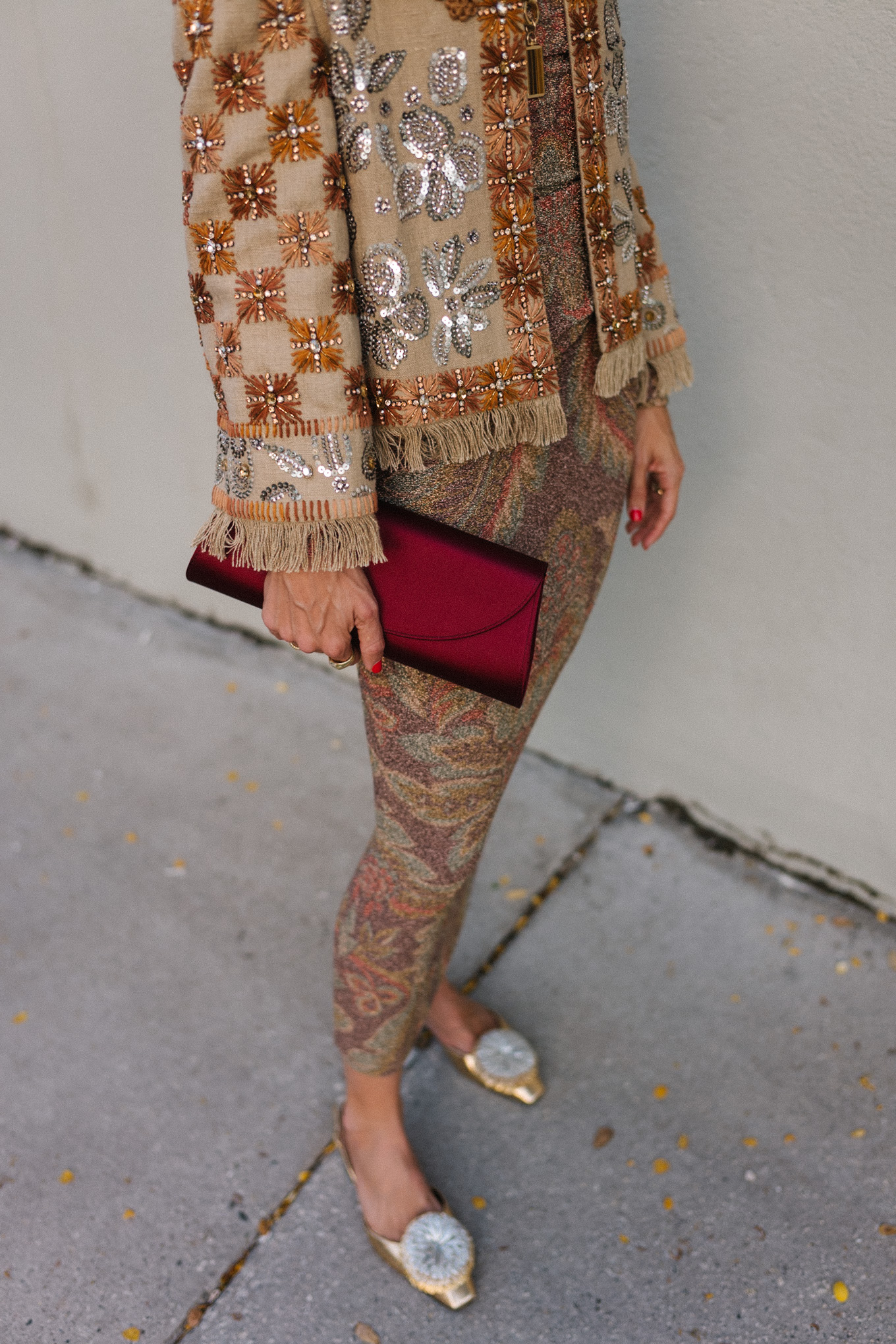 Veste ornée, jupe métallisée, chaussures plates à pompons, pochette en satin