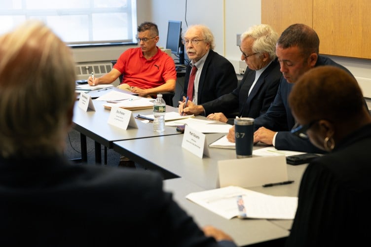 A group of people sitting at a row of tables.