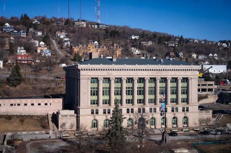 Un grand palais de justice beige avec de nombreux bâtiments résidentiels sur une colline derrière lui.