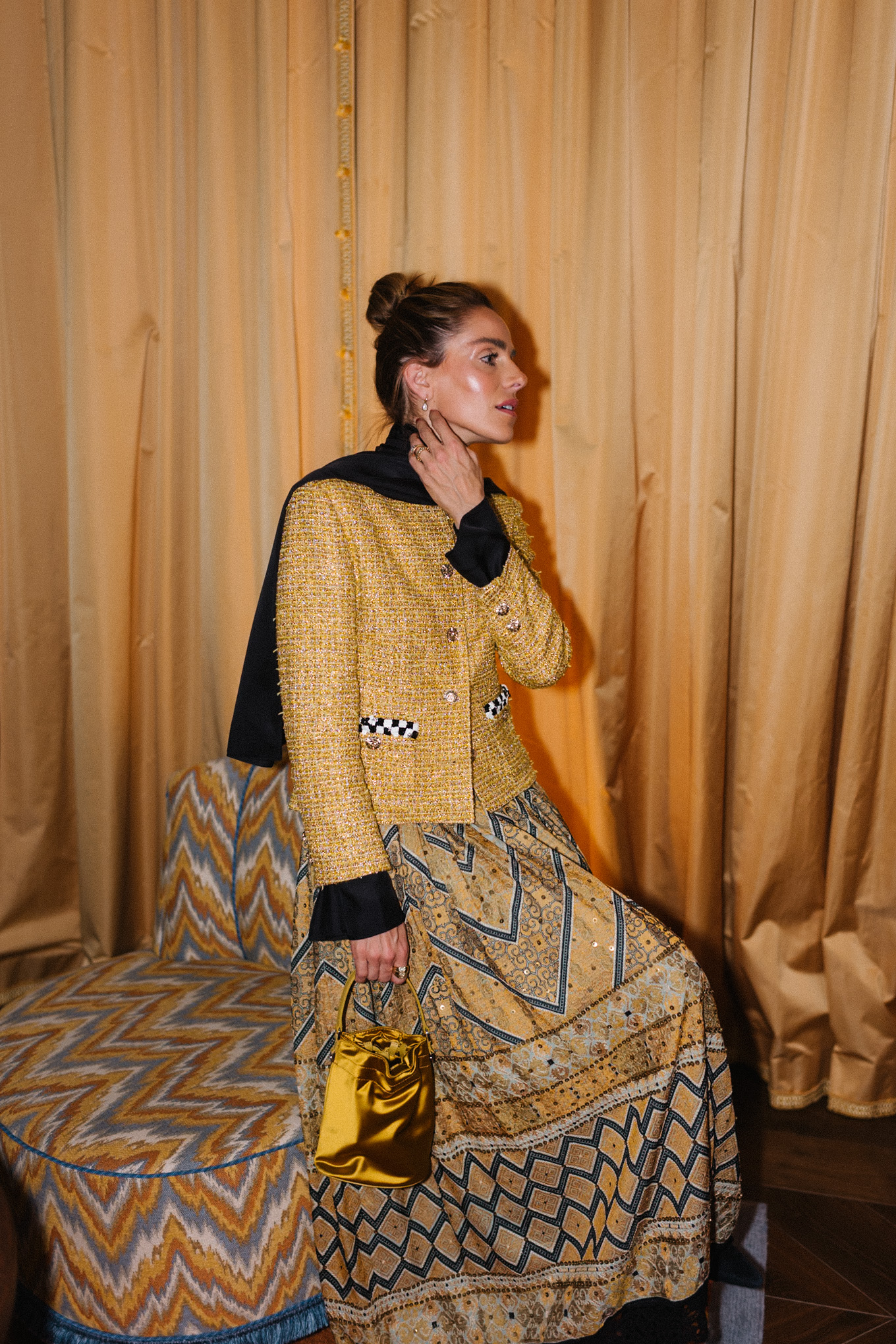 Veste en tweed doré, jupe imprimée dorée, sac seau en soie dorée, écharpe noire, bottes noires