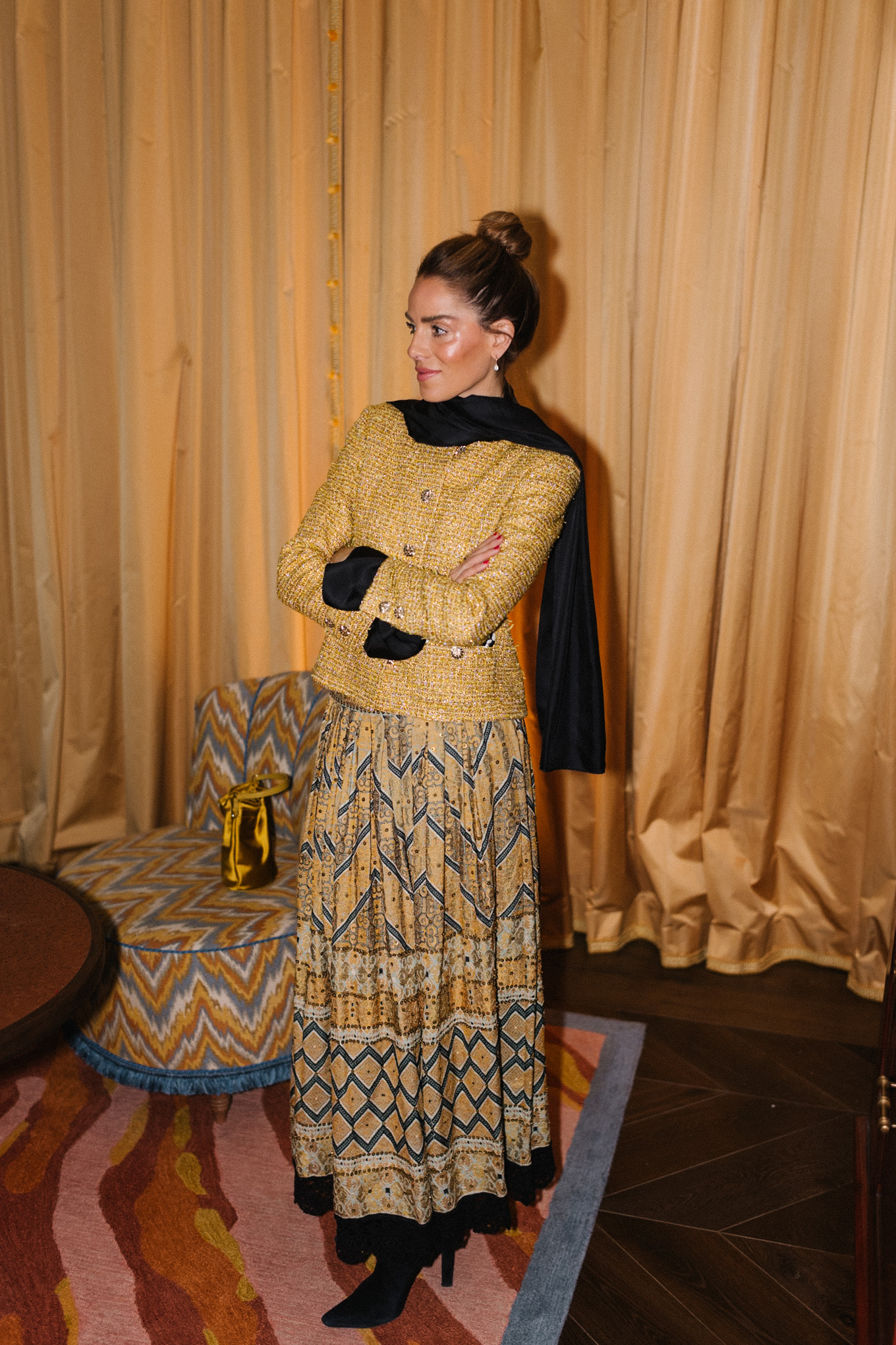 Veste en tweed doré, jupe imprimée dorée, sac seau en soie dorée, écharpe noire, bottes noires