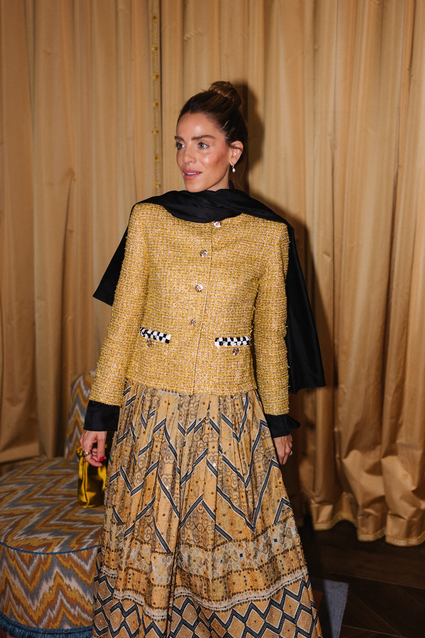 Veste en tweed doré, jupe imprimée dorée, sac seau en soie dorée, écharpe noire, bottes noires