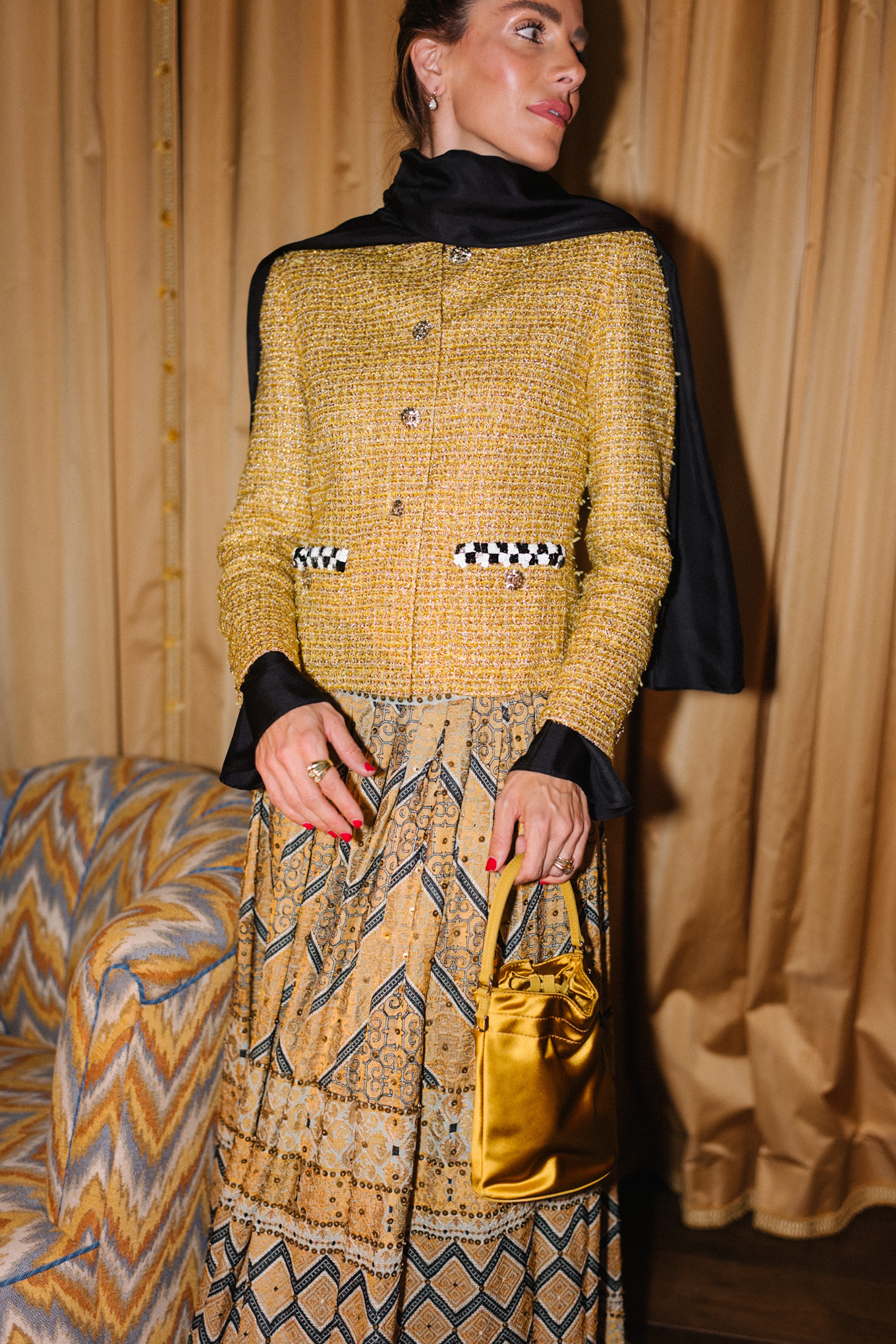 Veste en tweed doré, jupe imprimée dorée, sac seau en soie dorée, écharpe noire, bottes noires
