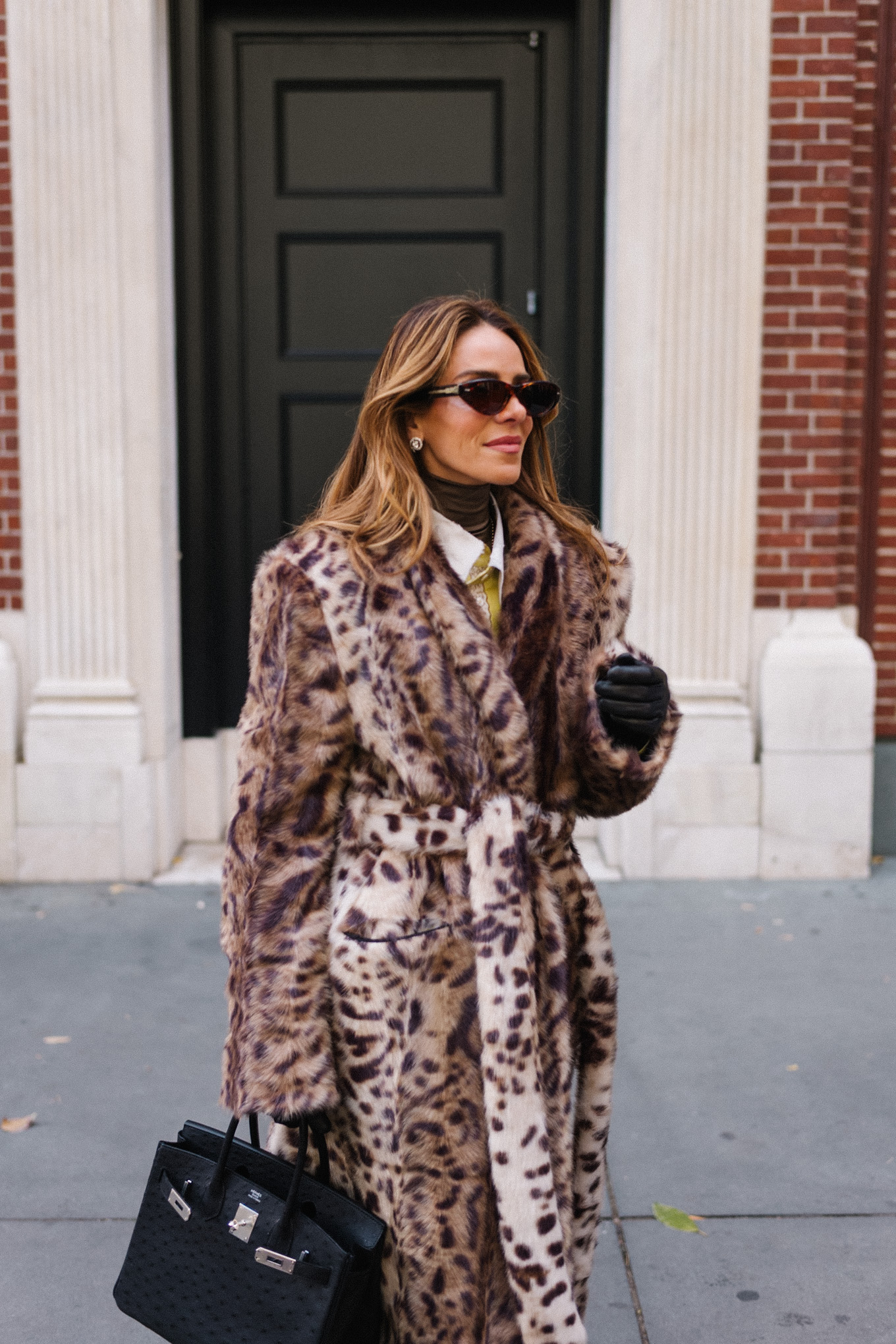 Manteau léopard, veste en soie, col roulé marron, ceinture à pompons, sac à main noir, gants noirs