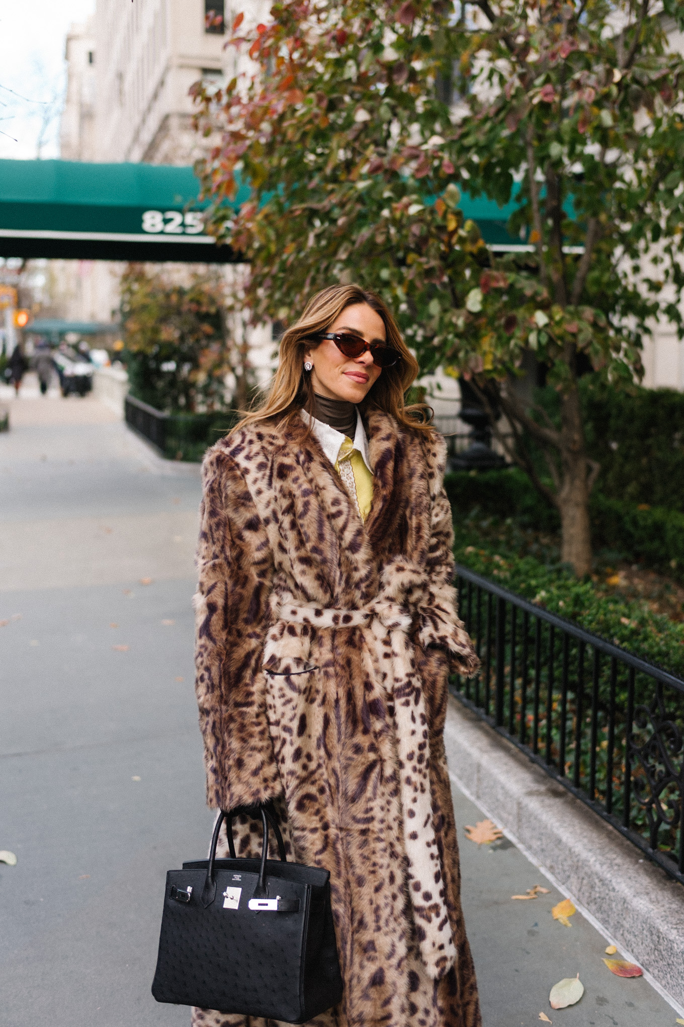 Manteau léopard, veste en soie, col roulé marron, ceinture à pompons, sac à main noir, gants noirs