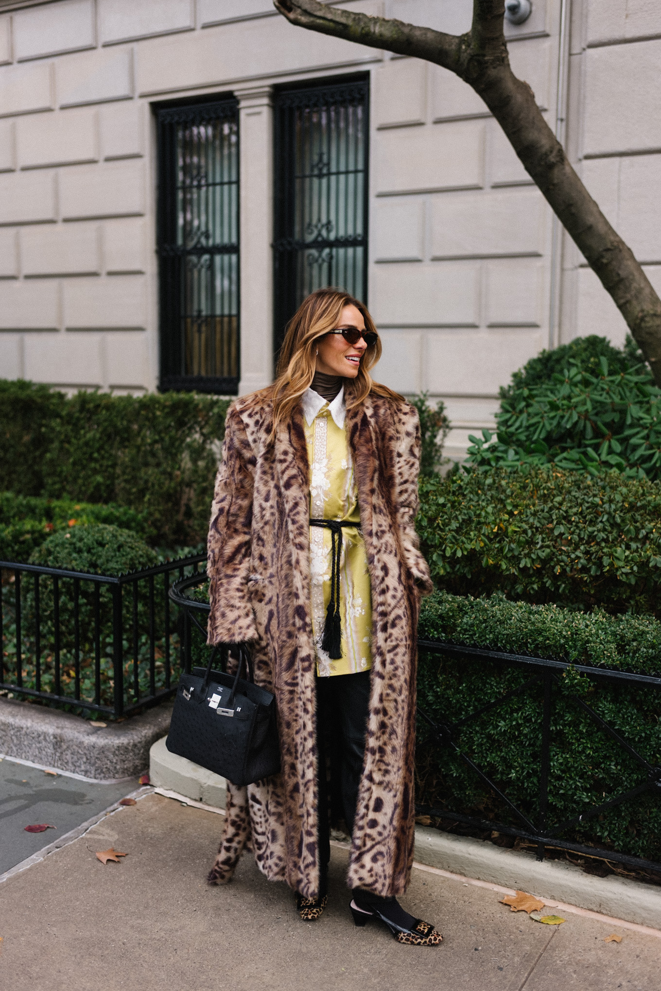 Manteau léopard, veste en soie, col roulé marron, ceinture à pompons, sac à main noir, gants noirs
