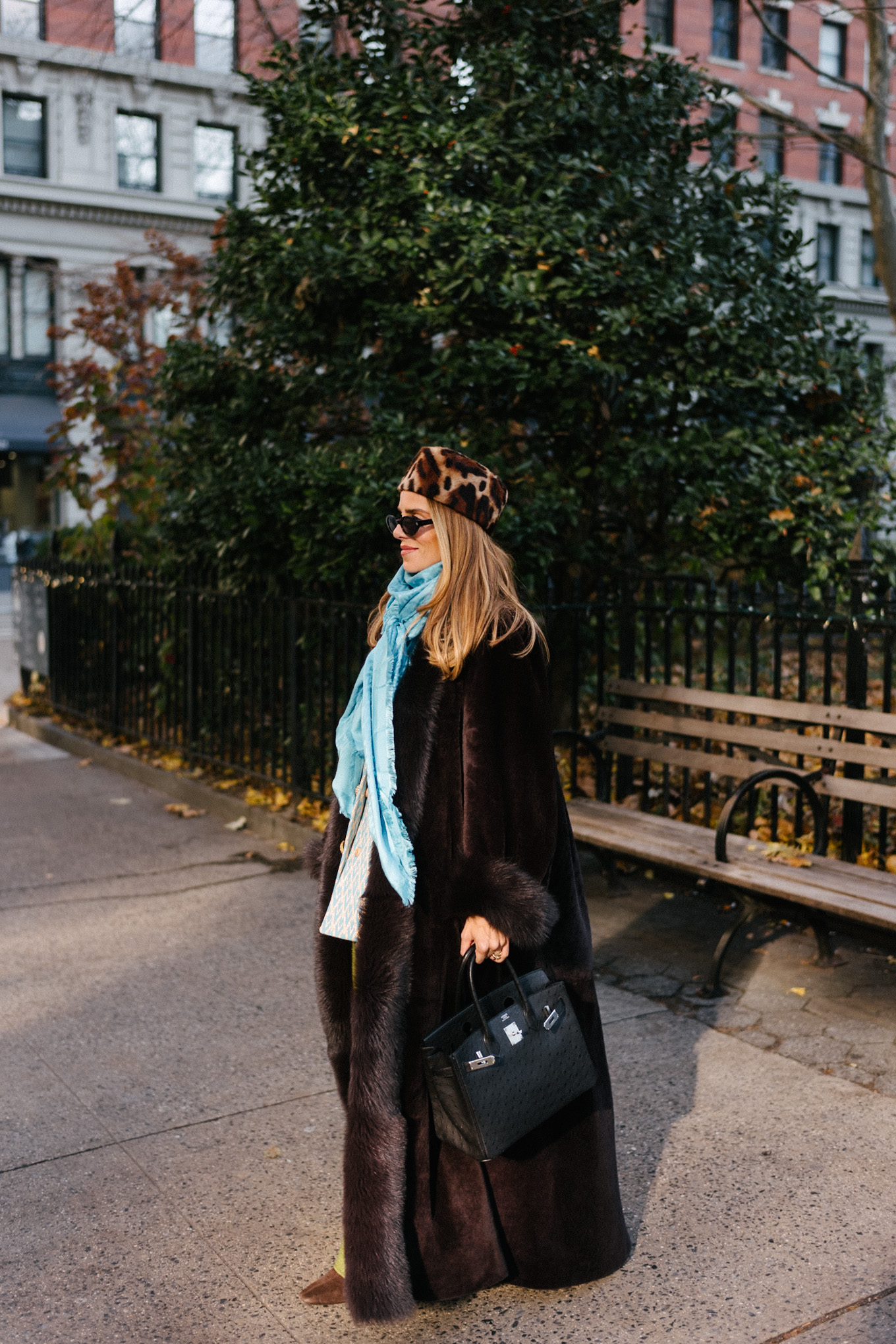 Manteau en peau lainée marron, chapeau casemate imprimé léopard, pantalon en satin vert, foulard en soie turquoise