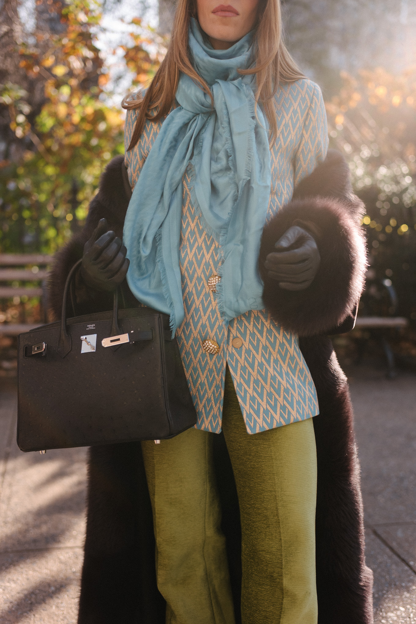 Manteau en peau lainée marron, chapeau casemate imprimé léopard, pantalon en satin vert, foulard en soie turquoise