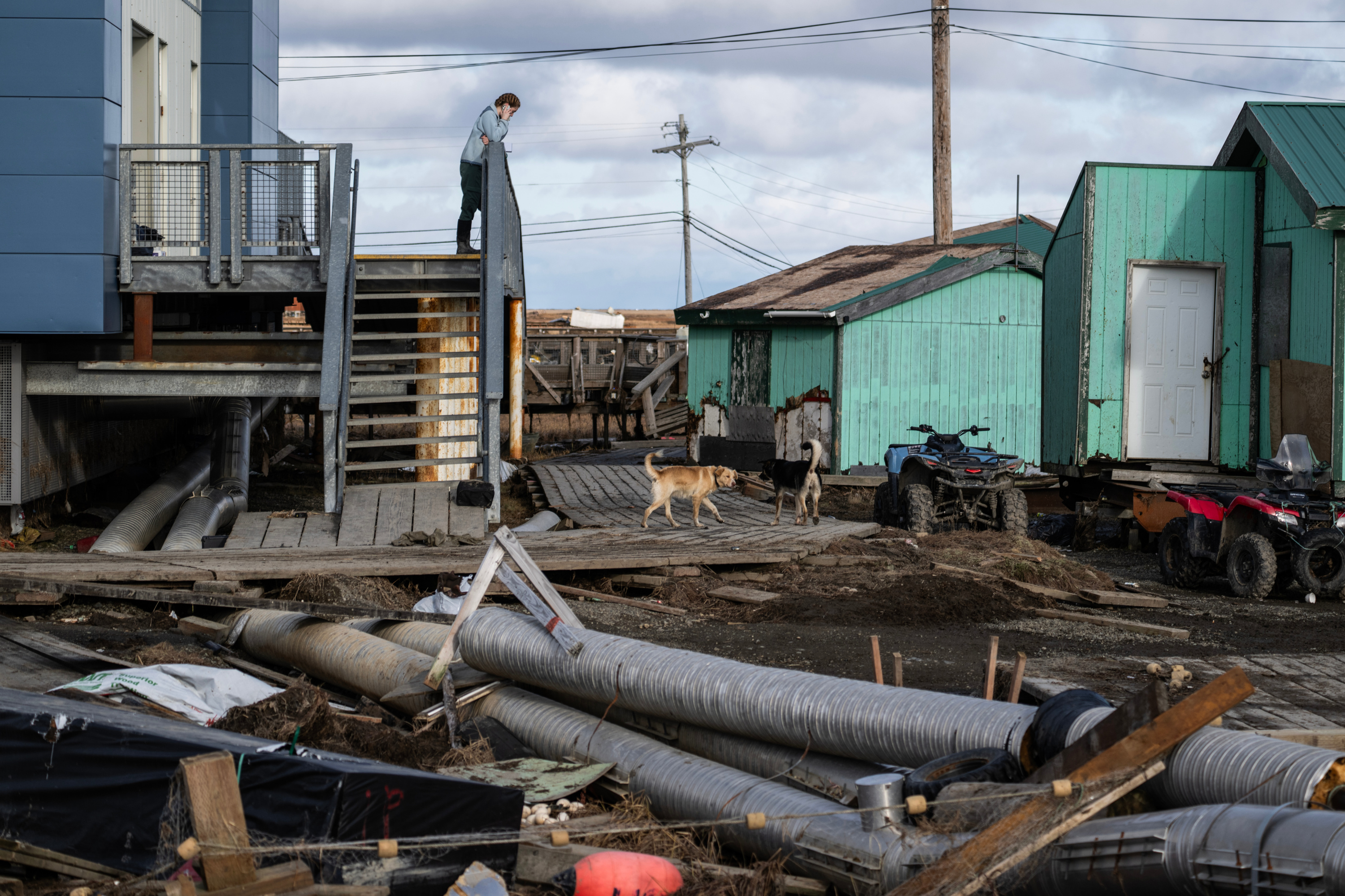 A person stands on a flight of stairs overlooking metal, wooden and plastic debris covering the ground.