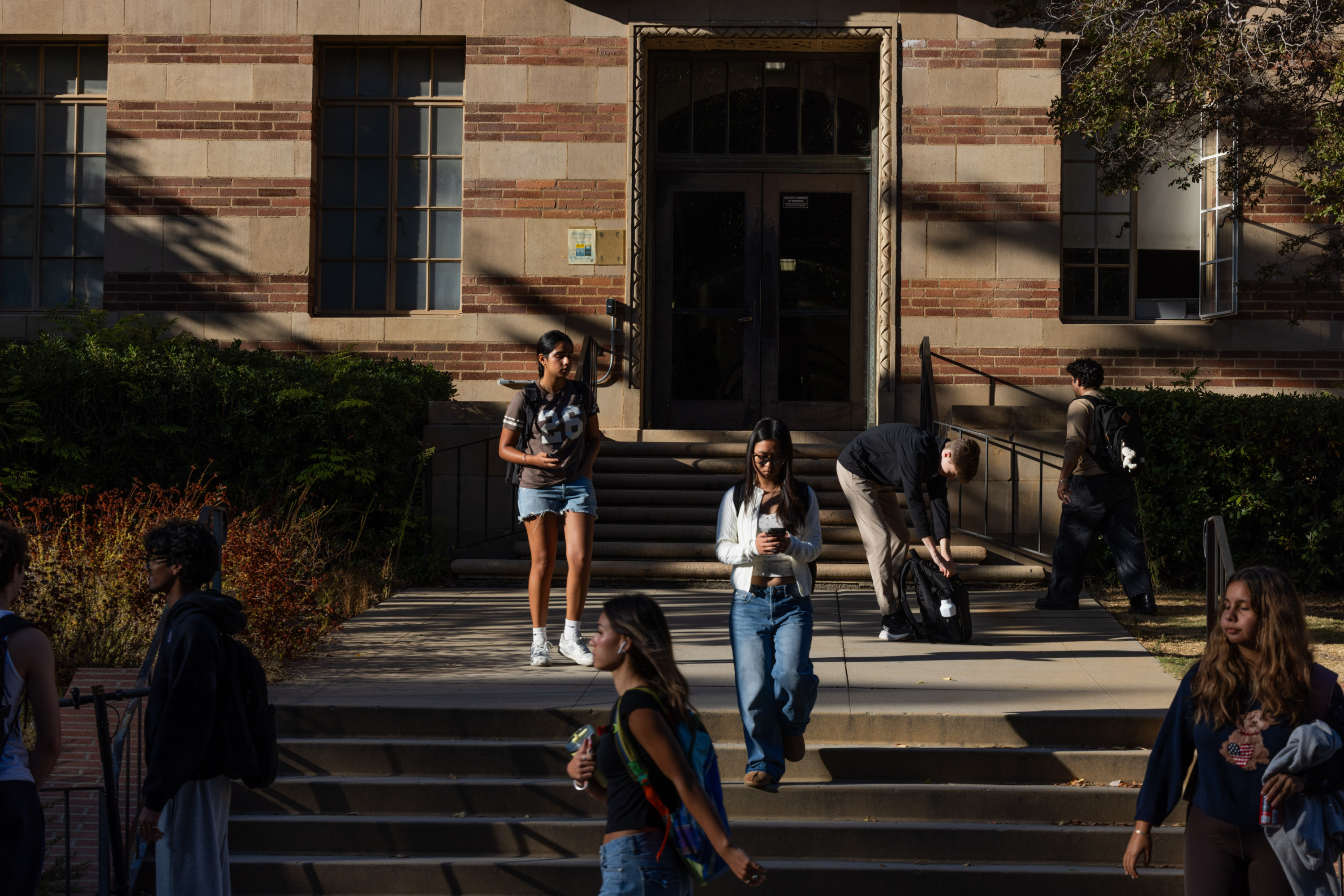 People walk on steps near a brick building.