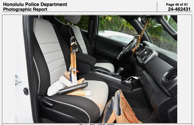 A bundle of wooden mallets with long heads on the passenger seat of a car with a black-and-white interior.