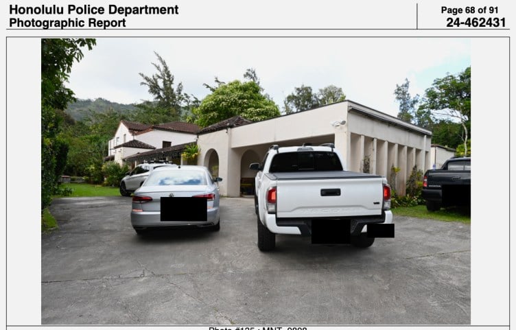 Part of a police report with a photograph of two cars and two trucks in front of a mansion surrounded by vegetation with no other buildings visible around it.