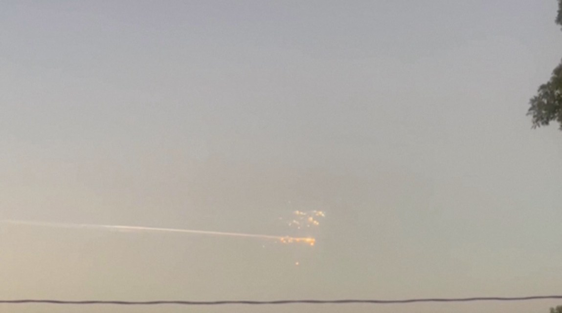 A streak of light across the sky with a collection of bright dots at the right-hand end of it.