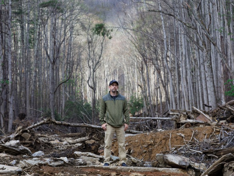 Ein Mann steht mitten auf einer Waldlichtung auf einem Haufen Schutt.