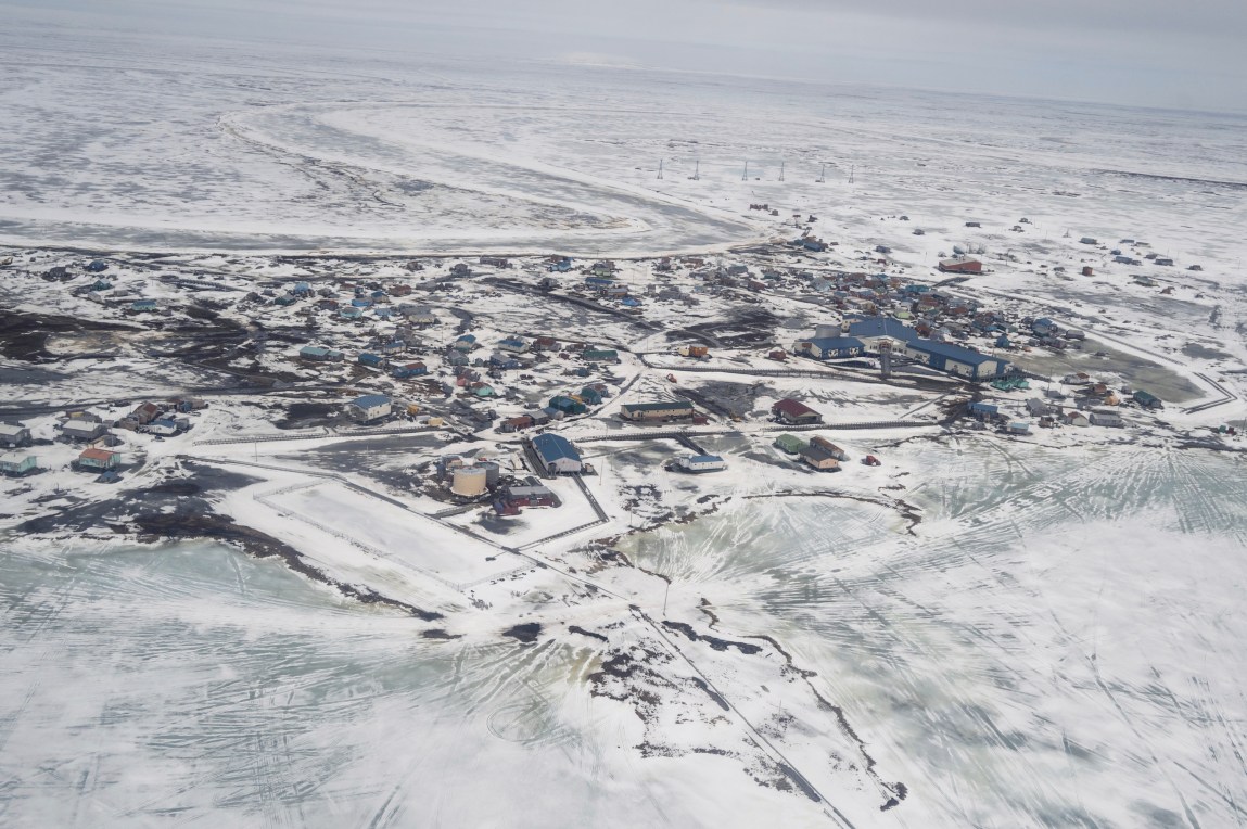 Une vue aérienne d’une ville enneigée au bord d’un plan d’eau.