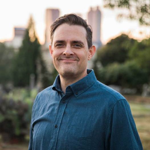 Ein Mann in einem blauen Hemd steht in einem Park.