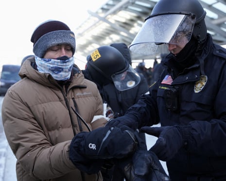 A police officer detains a protester outside Minneapolis-St. Paul International Airport, 23 January 2026.