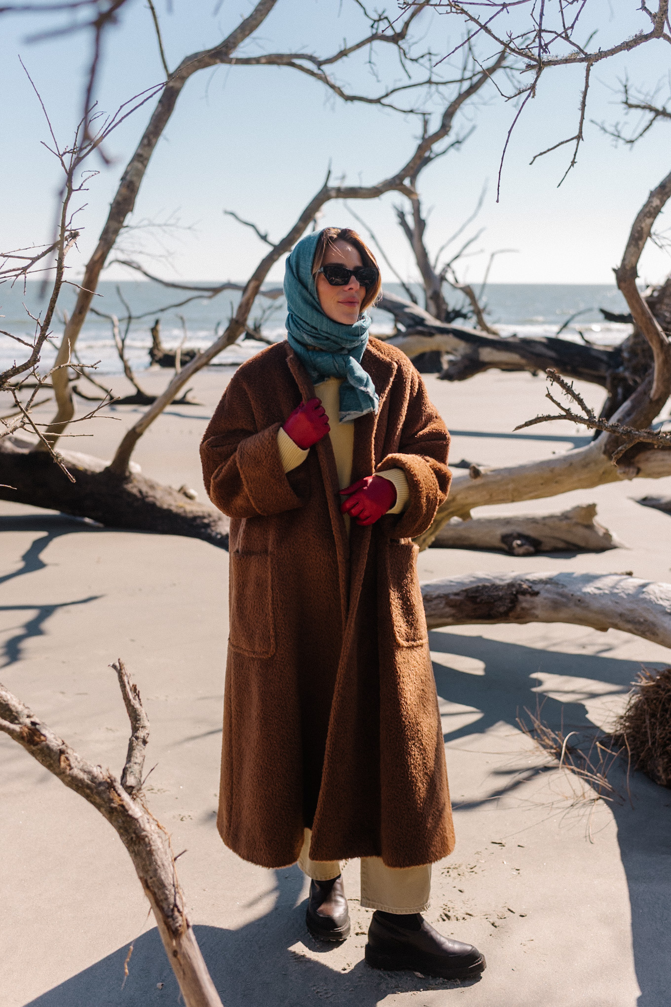 Manteau polaire surdimensionné marron, écharpe bleue, pull jaune, jean crème, bottes marron