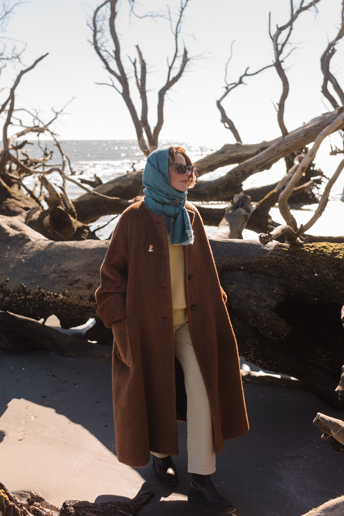 Manteau polaire surdimensionné marron, écharpe bleue, pull jaune, jean crème, bottes marron