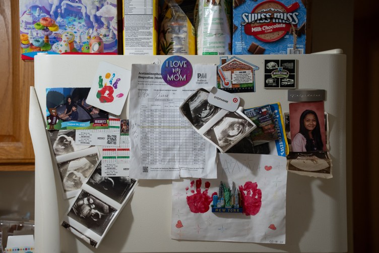 A refrigerator covered with paperwork,, family pictures, sonograms and children’s paintings.