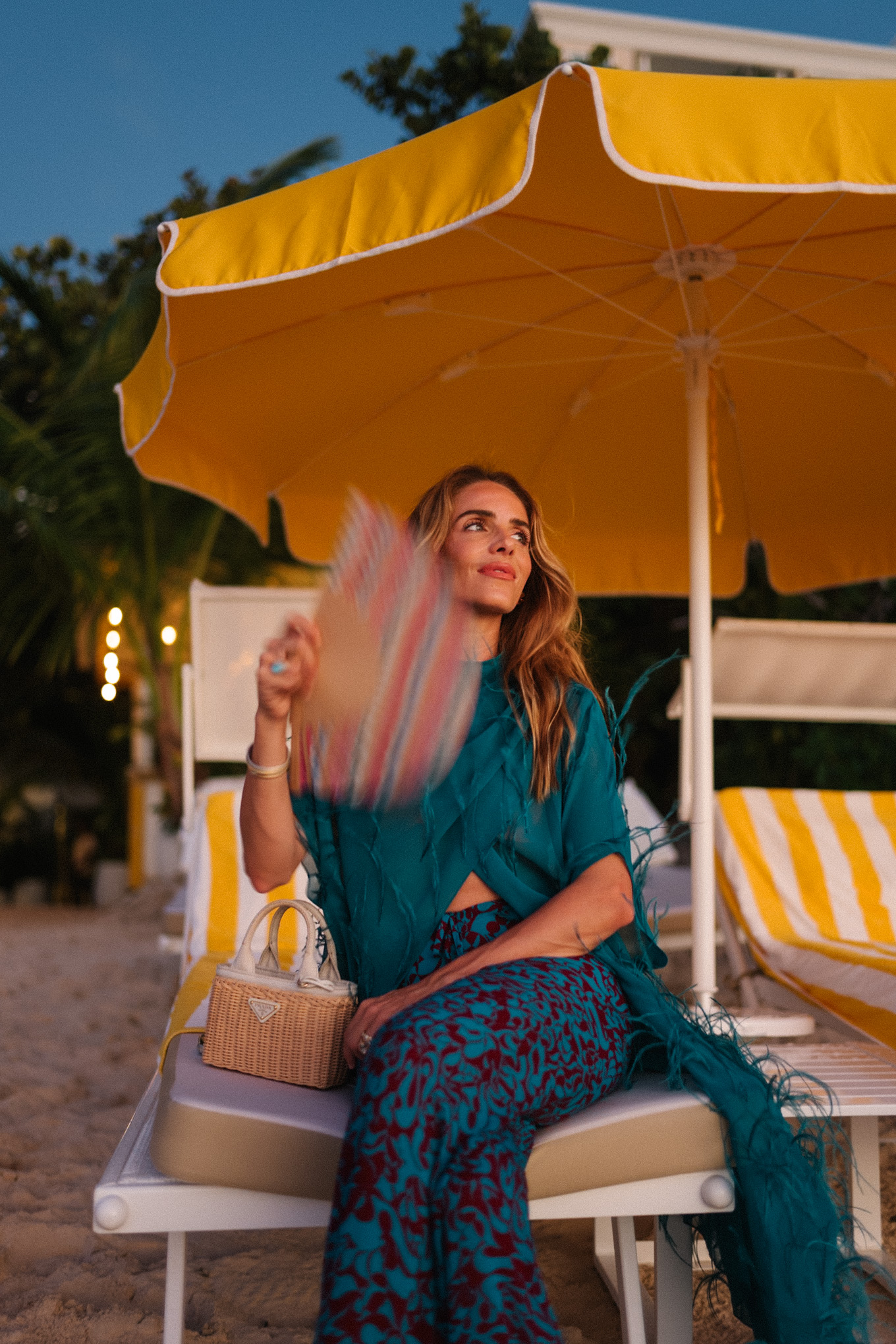 Haut maxi en plumes turquoise, pantalon large imprimé turquoise et sac à main en osier