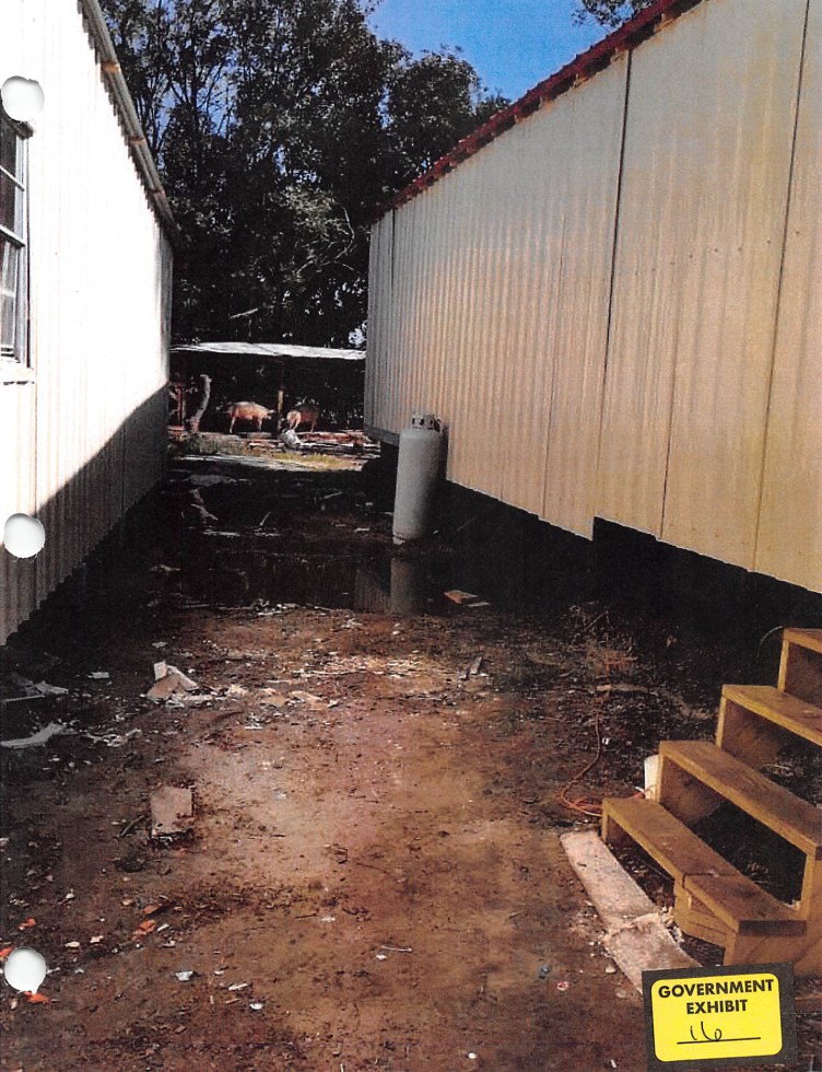 A dirt path covered in debris separates two buildings.
