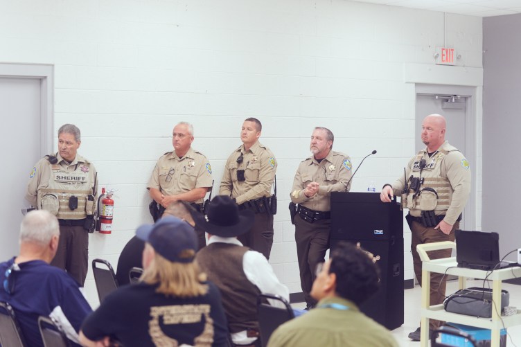 Five uniformed sheriff’s officers standing at the front of a large meeting space.