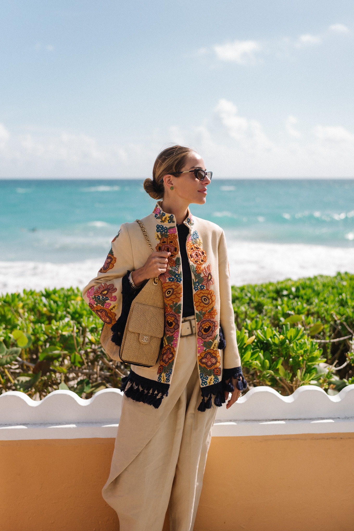 veste brodée, t-shirt noir, pantalon large en lin, sandales à lanières en cuir marron