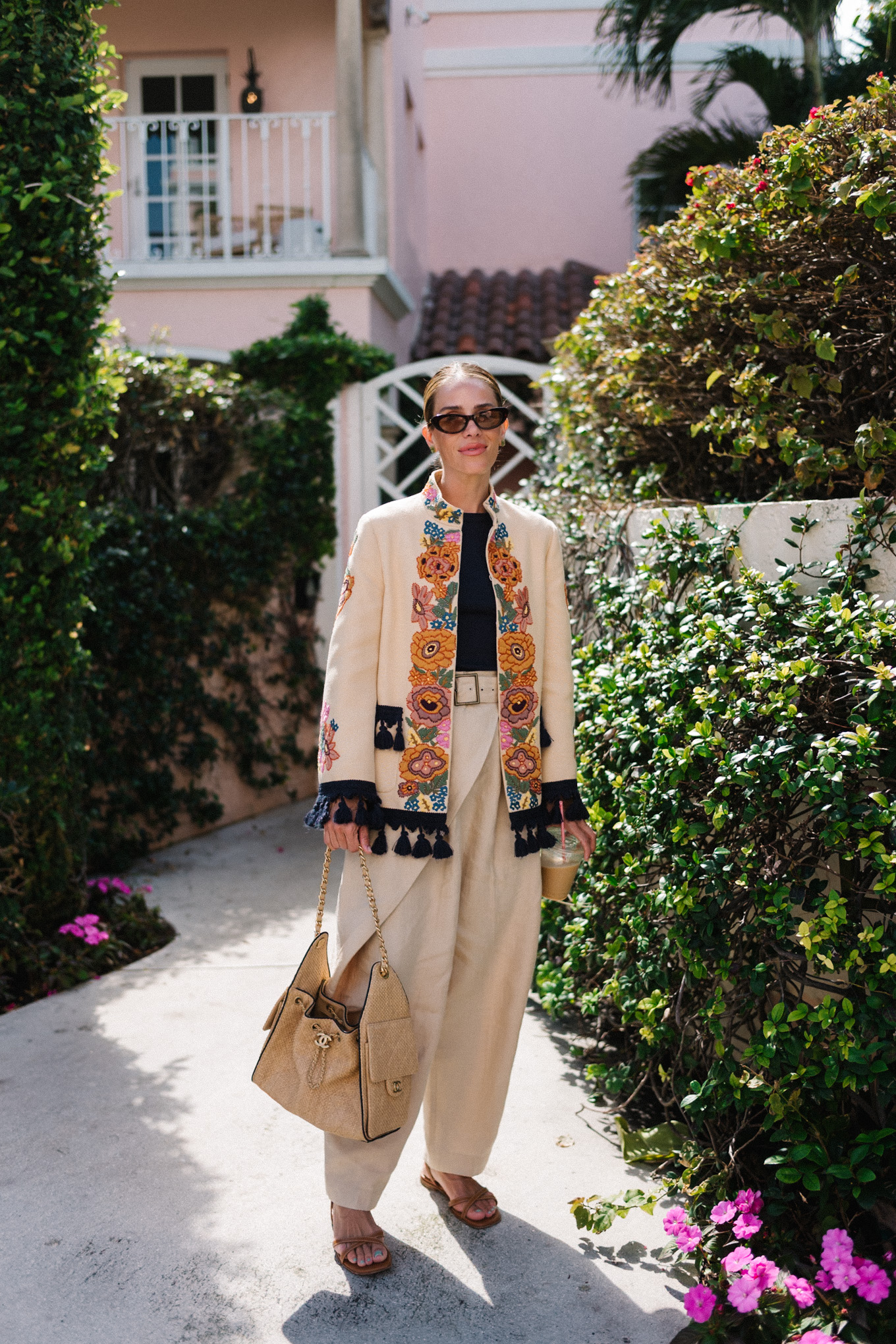 veste brodée, t-shirt noir, pantalon large en lin, sandales à lanières en cuir marron