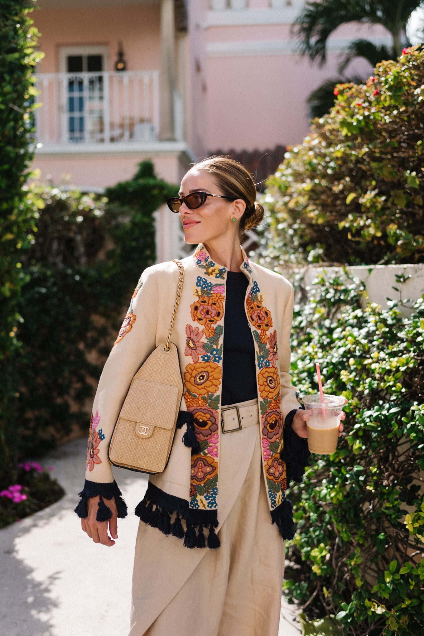 veste brodée, t-shirt noir, pantalon large en lin, sandales à lanières en cuir marron