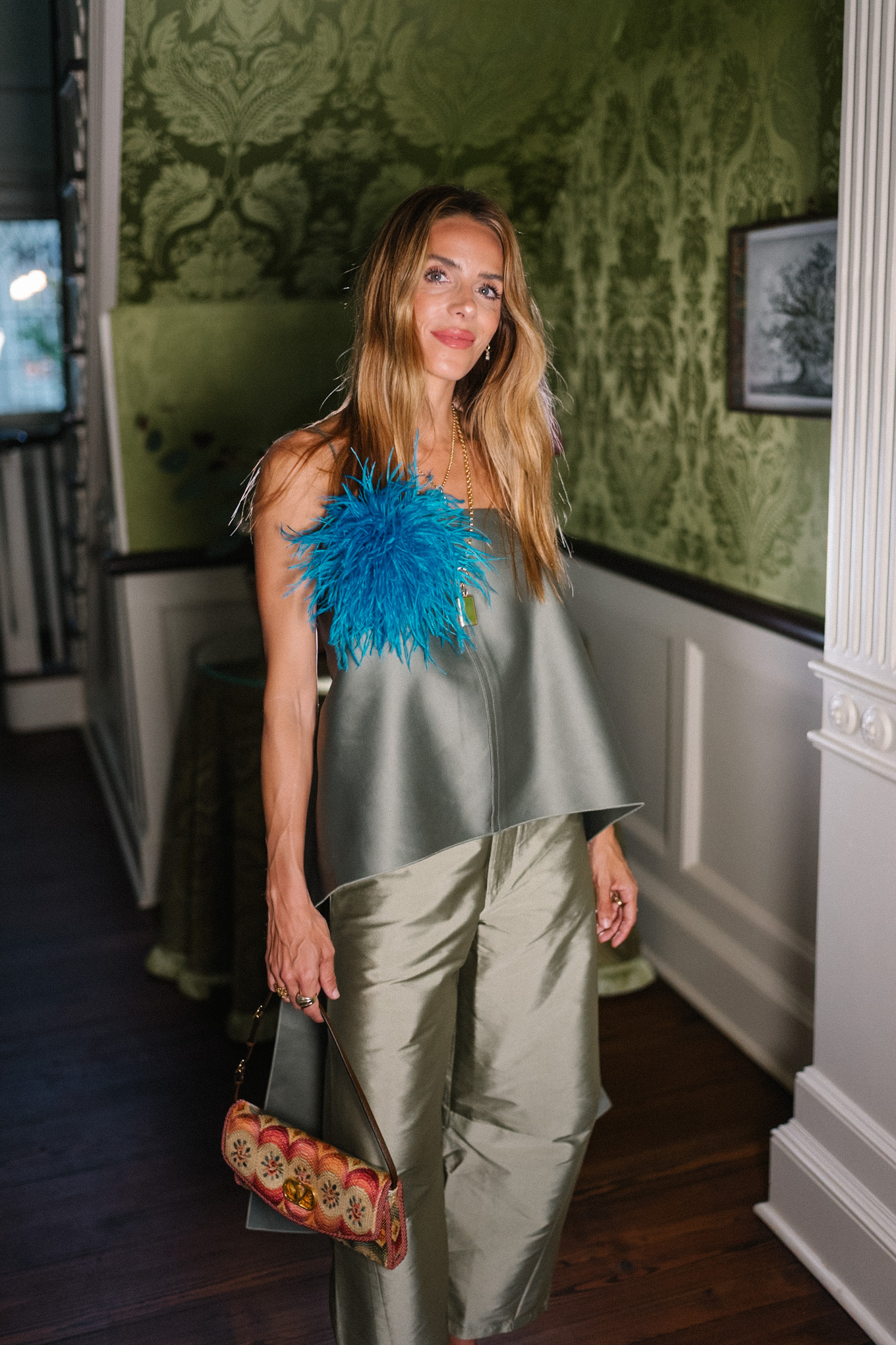 Débardeur vert, pantalon en taffetas vert, broche plume bleue