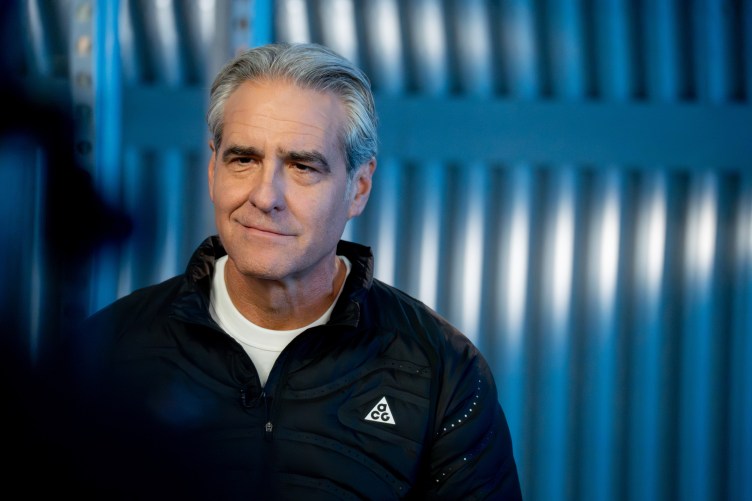 A man with silver hair in athletic wear smiles toward the camera.