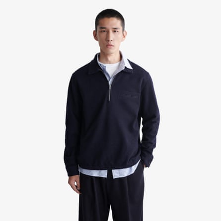 A model wears a Cos boiled-wool zip-up polo jumper with light blue collared shirt and whit tshirt layered beneath.