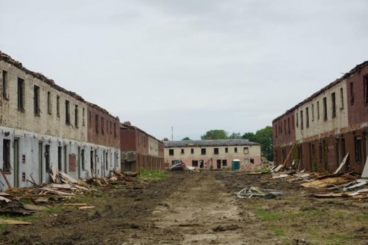 Plusieurs grands immeubles d'habitation sont partiellement détruits, leurs portes et façades s'entassent devant eux.
