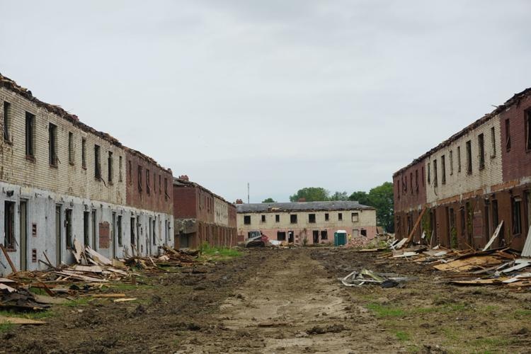 Several large apartment buildings are partially destroyed, with their doors and siding lying in piles in front of them.