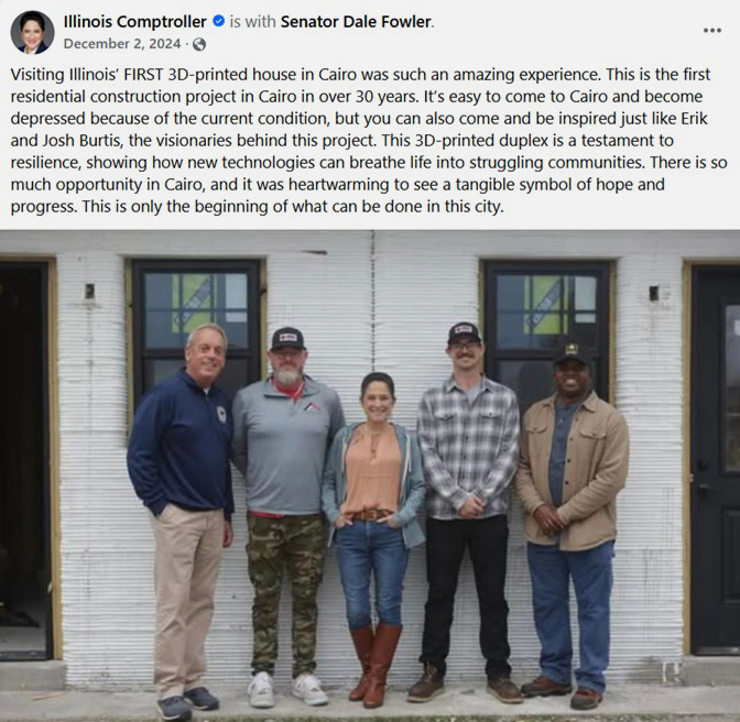 Four men and one woman stand in front of a partially built house, smiling at the camera.