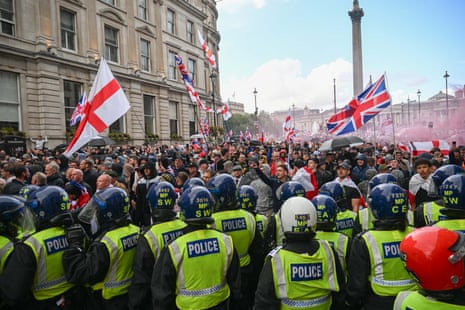 Des policiers en tenue anti-émeute regardent des milliers de personnes brandir des drapeaux anglais et l'Union Jack lors du rassemblement Unite the Kingdom à Londres.