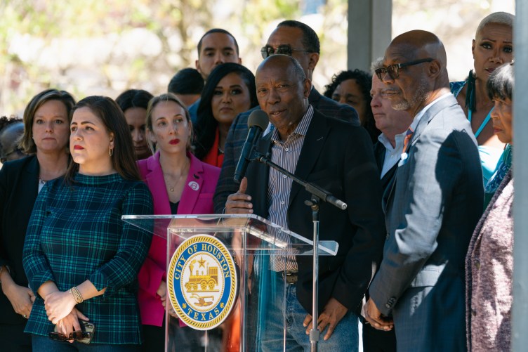 Ein Mann spricht während einer Pressekonferenz im Freien an einem Rednerpult mit dem Siegel der Stadt Houston, umgeben von einer Gruppe von Menschen.