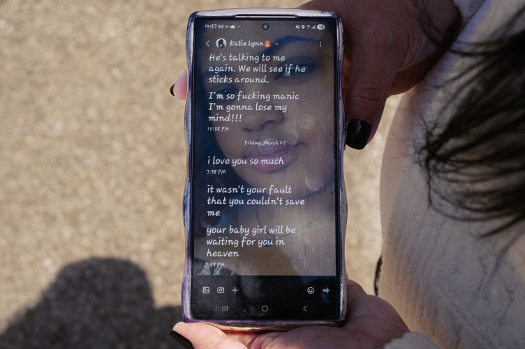 A close-up shot of a person holding a smartphone displaying a text message conversation overlaid onto a photo of a young woman's face. The contact name at the top is Katie Lynn.
The visible text messages read:
"He’s talking to me again. We will see if he sticks around."
"I’m so fucking manic I’m gonna lose my mind!!!" (10:38 PM)
There is a break between messages with the date listed as Friday, March 27. Then they resume:
"I love you so much" (7:38 PM)
"it wasn’t your fault that you couldn’t save me"
"your baby girl will be waiting for you in heaven" (7:39 PM).
